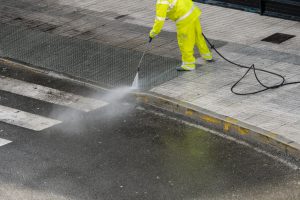 Worker cleaning the sidewalk with pressurized water